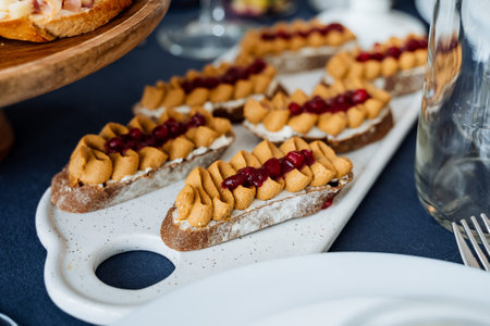 A beautifully arranged table features a tray overflowing with delicious sandwiches made from creamy...