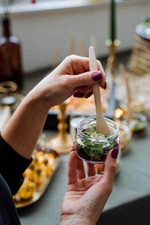 A woman is gracefully holding a jar filled with delicious food, using a wooden spoon to serve or perhaps mix the contents, displaying her connection to cooking and culinary delightsの写真素材