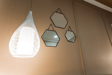 Three exquisitely crafted mirrors have been meticulously arranged on a wall adjacent to a sophisticated light fixture, which together enhance the overall ambiance and aesthetic appeal of the roomの写真素材