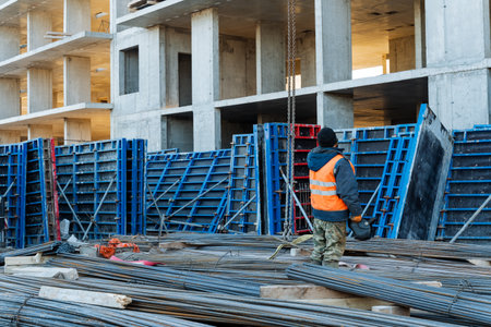 A dedicated construction worker stands confidently in front of a partially constructed building,...