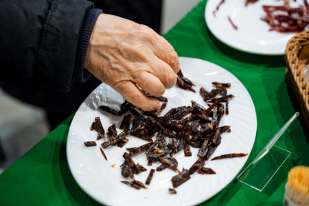 A hand reaches for a vibrant plate of dried chilies, showcasing the diverse flavors at a tasting event tailored for spice lovers and cooking enthusiasts who value seasoningの写真素材