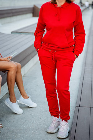 A fashionable woman is seen dressed in a bold and vibrant red sweatsuit, ideal for relaxed outings and maintaining comfortable chic looks in various urban environmentsの写真素材