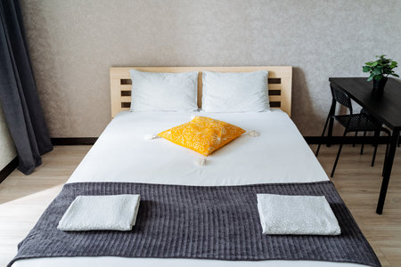 In a cozy, beautifully decorated bedroom, a neatly and carefully made bed adorned with a cheerful...