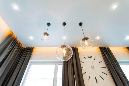 There is a cozy room featuring a clock mounted on the wall, along with elegant curtains that...