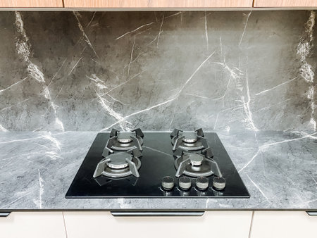 In a stylish kitchen, a gas stove is elegantly placed on a polished marble countertop, key for cooking delightful meals that bring joy to family and friends during gatheringsの写真素材