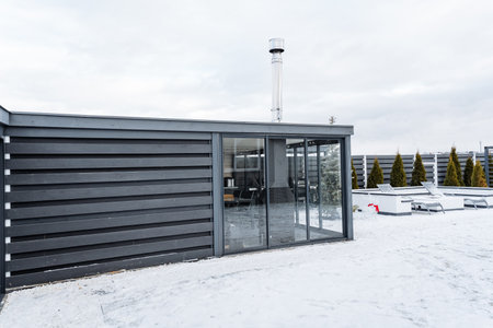 In a winter landscape, there is a building featuring a sliding glass door that is currently surrounded by a blanket of snow, creating a beautiful and serene scene in the cold weatherの写真素材