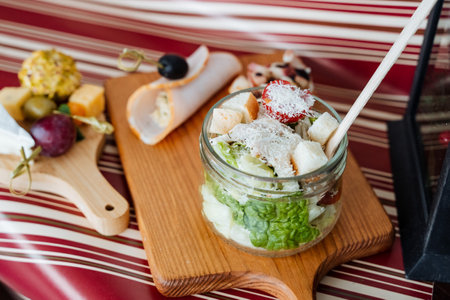 A jar of salad with a spoon in it is on a wooden cutting boardの写真素材