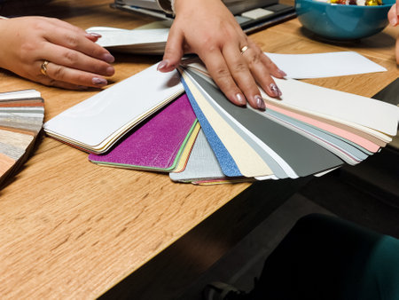 A woman is extending her hands towards a swatch of fabric that is placed on a table, showing her...
