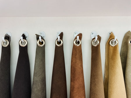 There is a neatly arranged row of luxurious brown towels that are hanging on sturdy hooks positioned...
