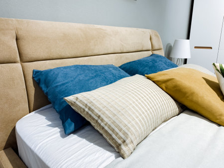 A beautifully designed bedroom features a charming bed with vibrant blue and yellow pillows, creating an inviting atmosphere of relaxation, comfort, and tranquility, perfect for retreatingの写真素材