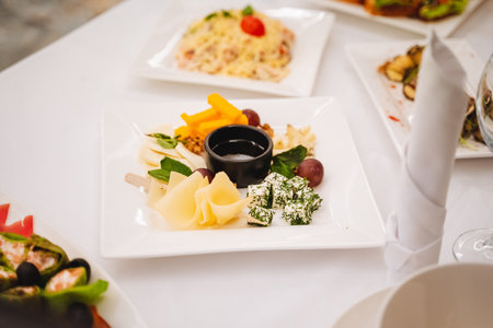 A beautifully arranged cheese platter featuring a delightful assortment of various cheeses, fresh...