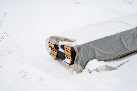 An object, securely covered with a protective tarp for safety, lies motionless in the deep, thick snow, creating a picturesque and serene winter scene that evokes the beauty of the seasonの写真素材