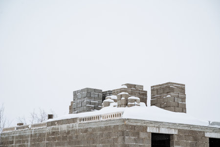A large building that is currently under construction has accumulated a thick layer of fluffy snow on its roof, creating a remarkable picturesque winter scene amidst the cold and frosty surroundingsの写真素材