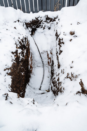 In the freezing cold, there is a noticeable hole in the untouched white snow, with a thin piece of wire protruding from it, creating an intriguing sight against the serene winter landscape around itの写真素材