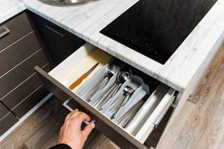 Discover the art of modern kitchen drawer organization featuring neatly arranged cutlery and utensils to enhance functionality for your cooking and dining experienceの写真素材