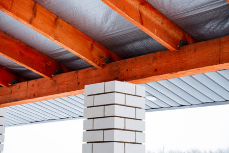 A traditional brick chimney situated beneath a sturdy roof that features beautiful, exposed wooden beams, creating a distinct architectural charm and inviting aesthetic atmosphereの写真素材