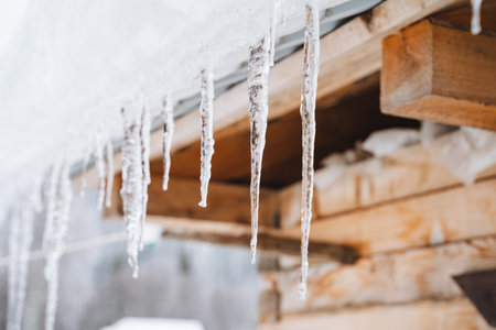 Marvelous and stunning icicles delicately hanging from a rustic wooden structure in this enchanting winter wonderland, showcasing natures serene and frosty beautyの写真素材