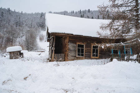 A picturesque log cabin, blanketed in a thick layer of snow, nestled in the heart of a serene, snowy forest, creating a cozy winter retreat surrounded by natures beautyの写真素材