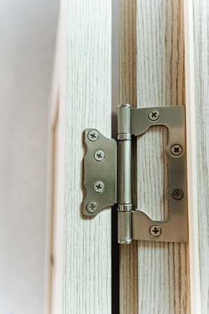 A close up of a door hinge on a wooden door