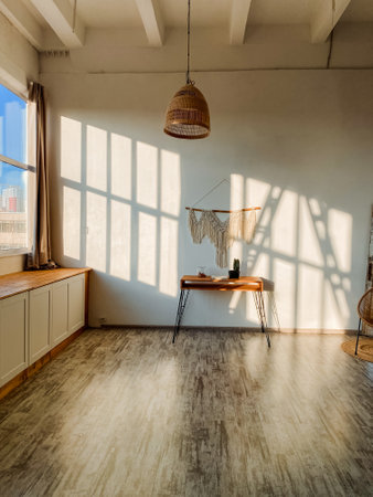 Imagine a cozy room with a beautifully crafted wooden floor, a modern desk against the wall, and a large window letting in abundant natural light, creating a warm, inviting atmosphereの写真素材