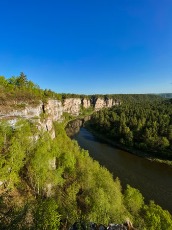 A picturesque river gracefully flowing through a serene valley that is beautifully surrounded by lush trees and rugged rocks, creating a stunning natural landscape full of diverse terrainの写真素材