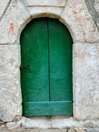 A beautifully crafted green door set within a robust stone archway significantly enhances the overall character and depth of the entire structure, creating a uniquely charming and inviting entrywayの写真素材