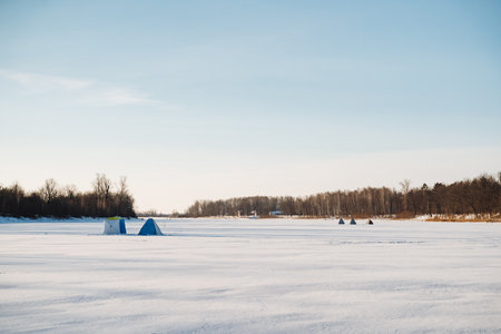 A group of enthusiastic individuals is engaging in the activity of ice fishing on a vast frozen lake, enjoying the chilly atmosphere and the beautiful winter landscape around themの写真素材