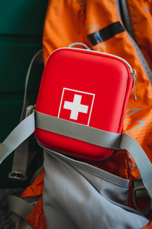 Inside a wellused backpack, there is a bright red first aid kit that features a prominent white cross symbolizing its purpose and importance in emergencies. It is an essential item for safetyの写真素材