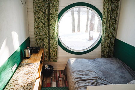 The spacious bedroom features a cozy bed along with a beautifully designed round window that allows natural light to flow in, creating a warm and inviting atmosphere for relaxationの写真素材