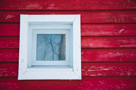 A bright white window stands out distinctly against a bold red wall, generating a striking visual effect that captivates the viewers attention and lingers in their mind long after they see itの写真素材