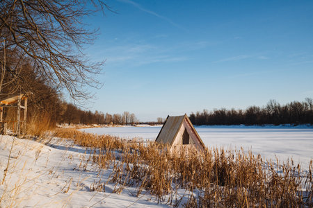 A quaint, small hut is peacefully sitting in the middle of a vast, snowy field, surrounded by the serene winter landscape, evoking a sense of tranquility and solitude in this icy environmentの写真素材
