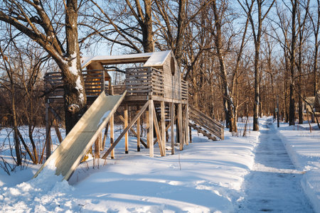 In a snowy playground, a colorful slide captivates children as they slide down. Nearby, a charming house enhances this winter scene, embodying the joyful essence of childhood and funの写真素材