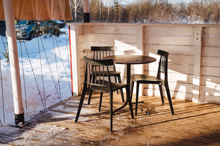 The cozy patio, with its elegant table and plush chairs, transforms dramatically under a thick layer of snow, creating a stunning winter scene that captivates the eye and imaginationの写真素材