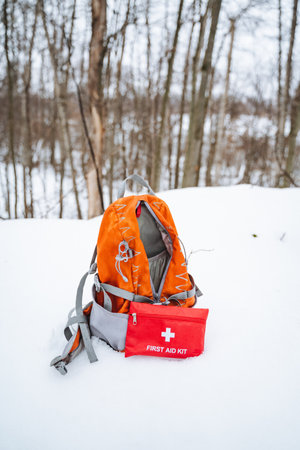 A bright and sturdy backpack along with a wellstocked first aid kit are resting on the cold, glistening snow, ready for any adventure or emergency that might arise in the great outdoorsの写真素材