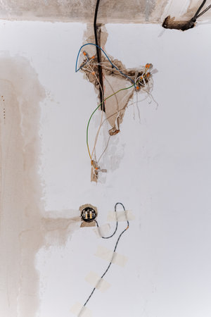 A multitude of wires are hanging down from the ceiling against a background of a crisp white wall, creating an intriguing visual contrast that combines industrial elements with minimalist aestheticsの写真素材