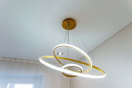 In a beautifully designed room, there is an elegant chandelier that features three stunning rings,...