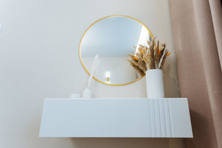 A sleek white shelf showcases a vibrant vase of colorful flowers, complemented by a chic wallmounted mirror, creating an elegant and inviting atmosphere for all who enter the roomの写真素材