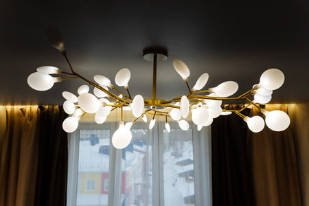 A beautifully crafted chandelier is gracefully hanging from the ceiling in a modern living room,...