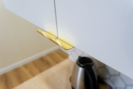 The elegant kitchen beautifully features contemporary golden lighting, a stylish kettle perched on a warm wooden floor, enhancing the homes modern and inviting aestheticの写真素材