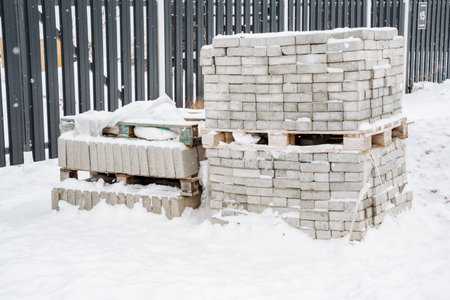 Piles of bricks and pavers, thoroughly blanketed in a thick layer of snow, create a striking visual during the winter season, showcasing the beauty of the cold weatherの写真素材
