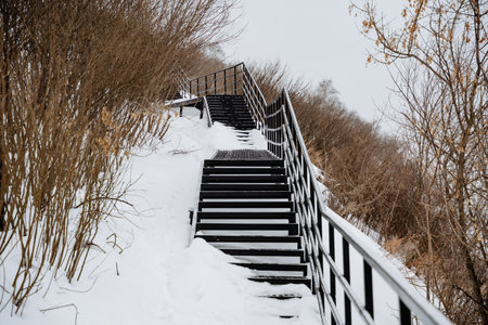 A staircase gracefully ascends a snowcovered hill, perfectly surrounded by enchanting winter scenery and the invigorating chill that fills the freezing air around itの写真素材
