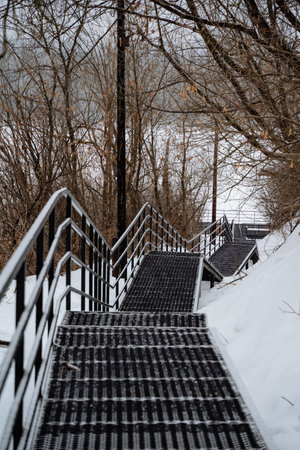 A staircase ascends a snowy hill, creating a tranquil winter scene. It has a sturdy handrail for climbers to navigate the slope safely and comfortably without slippingの写真素材