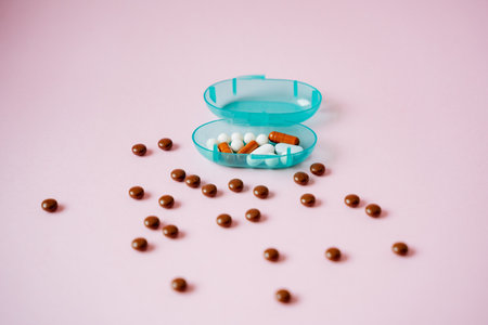 A bright blue container that is overflowing with an assortment of colorful pills and small brown...