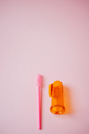 On a lovely pink background, there is a vibrant pink brush alongside a bright orange finger brush, creating a delightful contrast that emphasizes their unique colors and shapesの写真素材