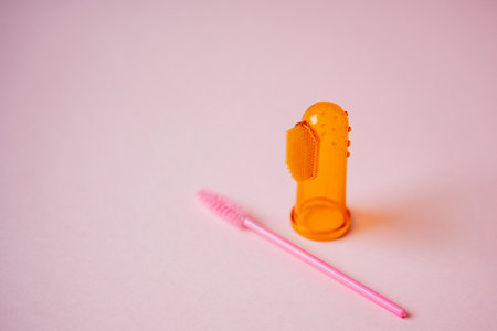 An orange finger brush and a pink brush rest peacefully on a soft pink surface, creating a vibrant and appealing color contrast that captivates attention through their unique and distinct shapesの写真素材