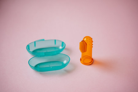 On a pink surface, there is a blue container paired with an orange container, creating a colorful display. Both are made of plastic.の写真素材