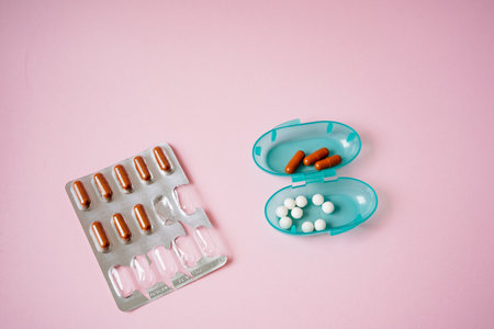 An arrangement featuring a blister pack filled with pills alongside a container that also holds...