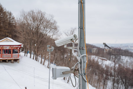 A camera is mounted atop a very tall pole, capturing a snow-covered landscape, where numerous...