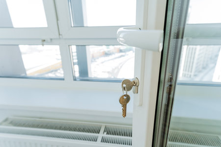 This image shows a closeup of an elegant window with a key in its lock, highlighting the intricate design and impressive functionality of the locking mechanism as a fine piece of craftsmanshipの写真素材