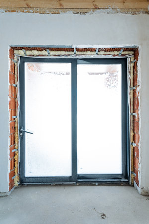 In an empty room, a sliding glass door is currently being installed, which will enhance both the aesthetics and functionality of the space being prepared for future use and enjoymentの写真素材